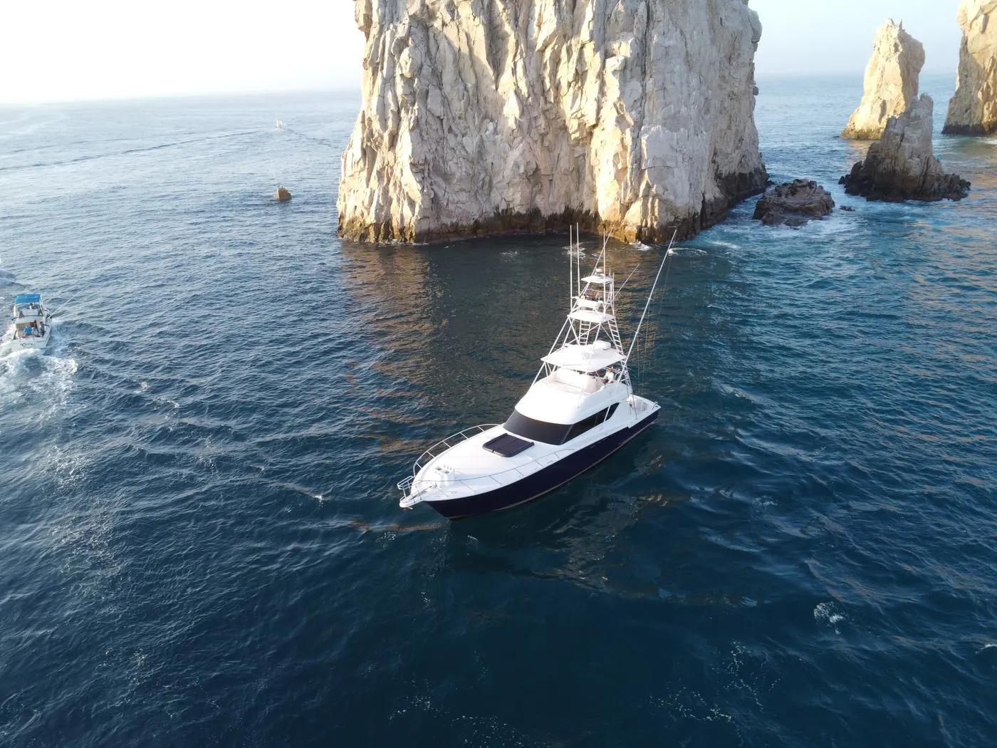 Aerial drone view of Lion Heart 60ft Hatteras sport fishing yacht near the rocks of Cabo San Lucas